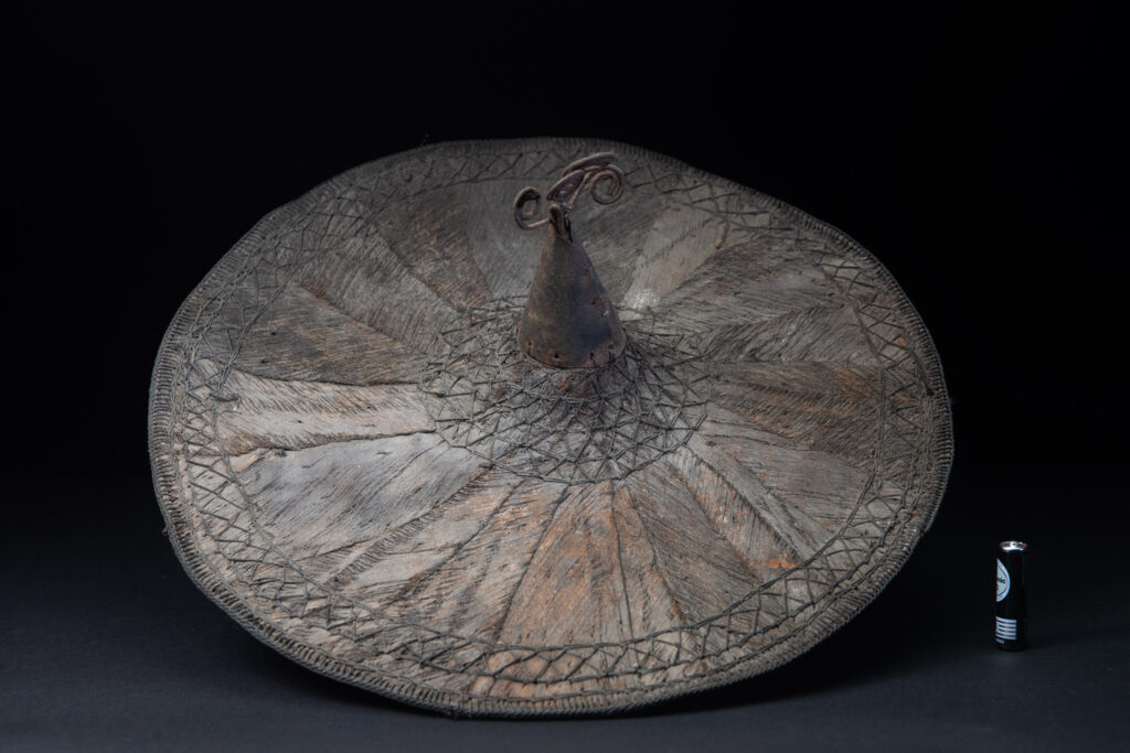 This ancient hat from the Yami- Tao tribes, orchid Island, Taiwan was worn by the female for work in the fields It is named “Varogot”. It is done with coconut palm bark, rotaing, aluminium and iron for the top decoration..