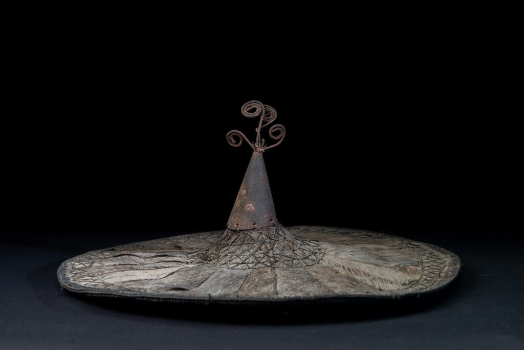 This ancient hat from the Yami- Tao tribes, orchid Island, Taiwan was worn by the female for work in the fields It is named “Varogot”. It is done with coconut palm bark, rotaing, aluminium and iron for the top decoration..