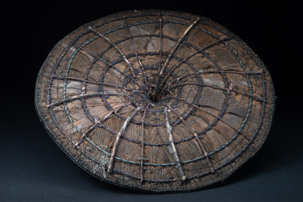 This ancient hat from the Yami- Tao tribes, orchid Island, Taiwan was worn by the female for work in the fields It is named “Varogot”. It is done with coconut palm bark, rotaing, aluminium and iron for the top decoration..