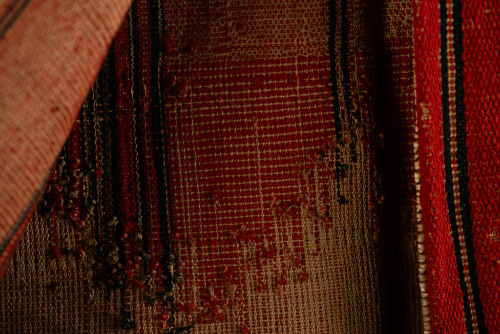 19 century Long men's jacket from the Atayal tribe, entirely woven in red with black and white stripes, and adorned with bone beads along the edges.