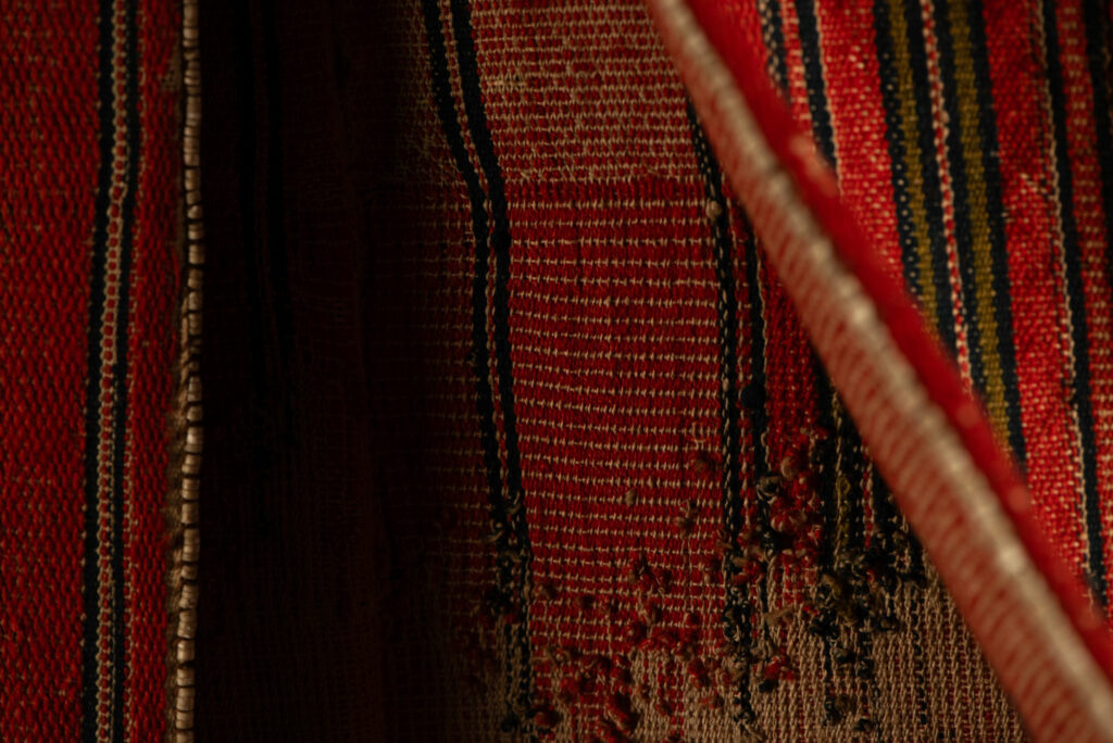 19 century Long men's jacket from the Atayal tribe, entirely woven in red with black and white stripes, and adorned with bone beads along the edges.