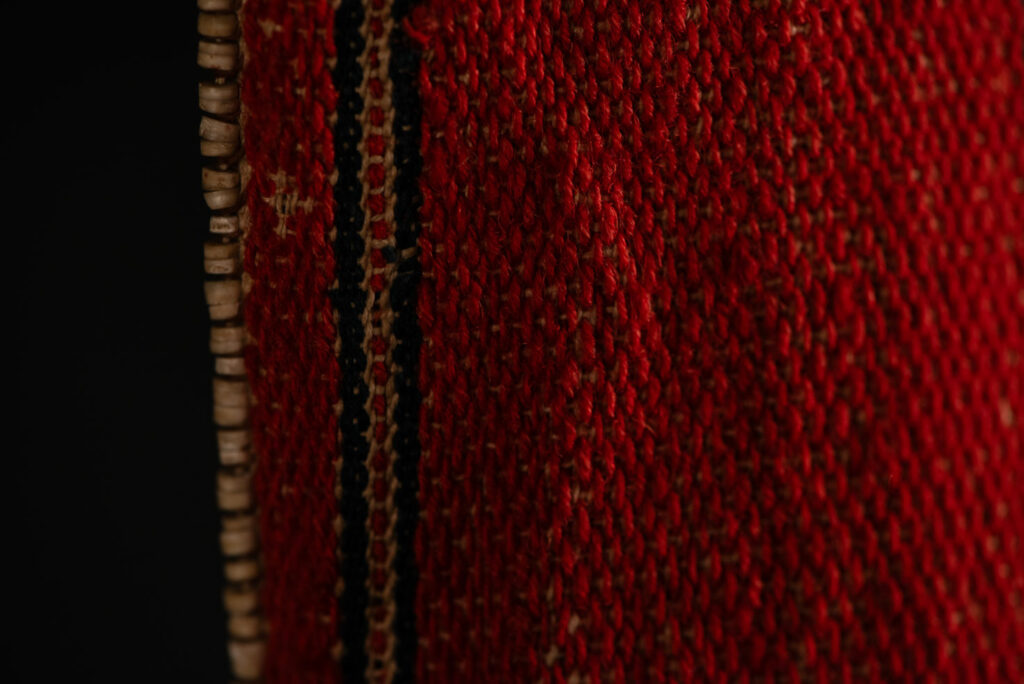 19 century Long men's jacket from the Atayal tribe, entirely woven in red with black and white stripes, and adorned with bone beads along the edges.