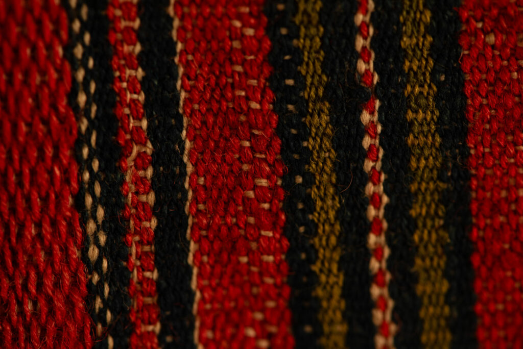 19 century Long men's jacket from the Atayal tribe, entirely woven in red with black and white stripes, and adorned with bone beads along the edges.