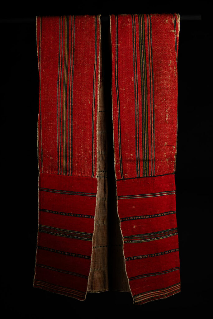 19 century Long men's jacket from the Atayal tribe, entirely woven in red with black and white stripes, and adorned with bone beads along the edges.