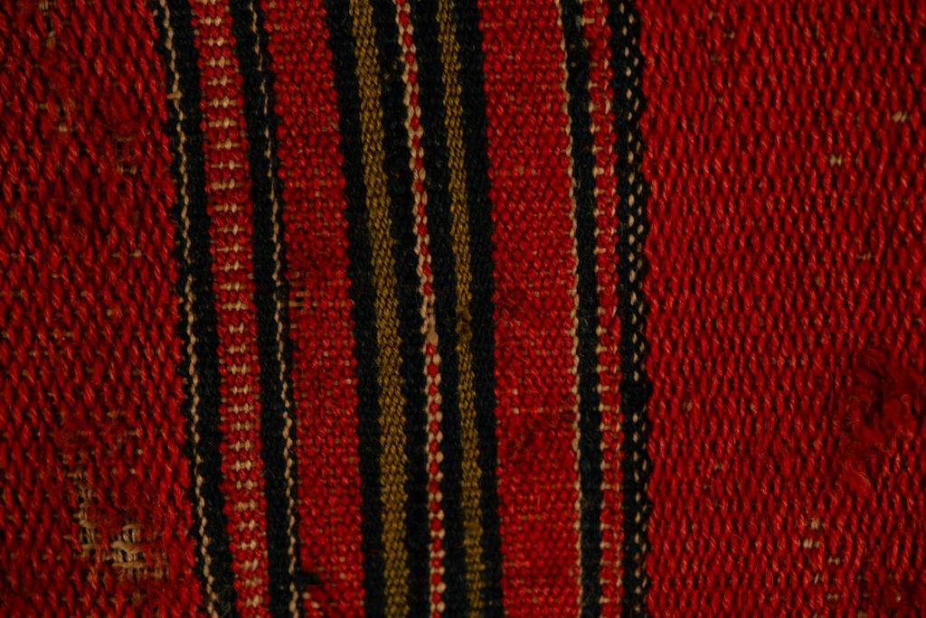 19 century Long men's jacket from the Atayal tribe, entirely woven in red with black and white stripes, and adorned with bone beads along the edges.
