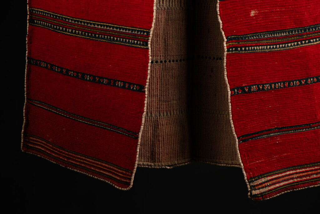 19 century Long men's jacket from the Atayal tribe, entirely woven in red with black and white stripes, and adorned with bone beads along the edges.