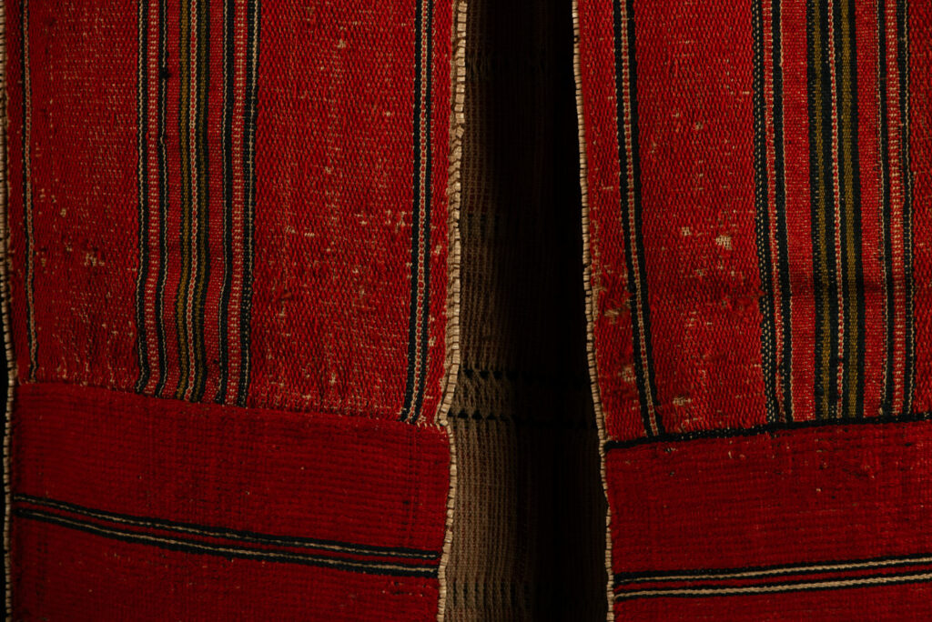 19 century Long men's jacket from the Atayal tribe, entirely woven in red with black and white stripes, and adorned with bone beads along the edges.