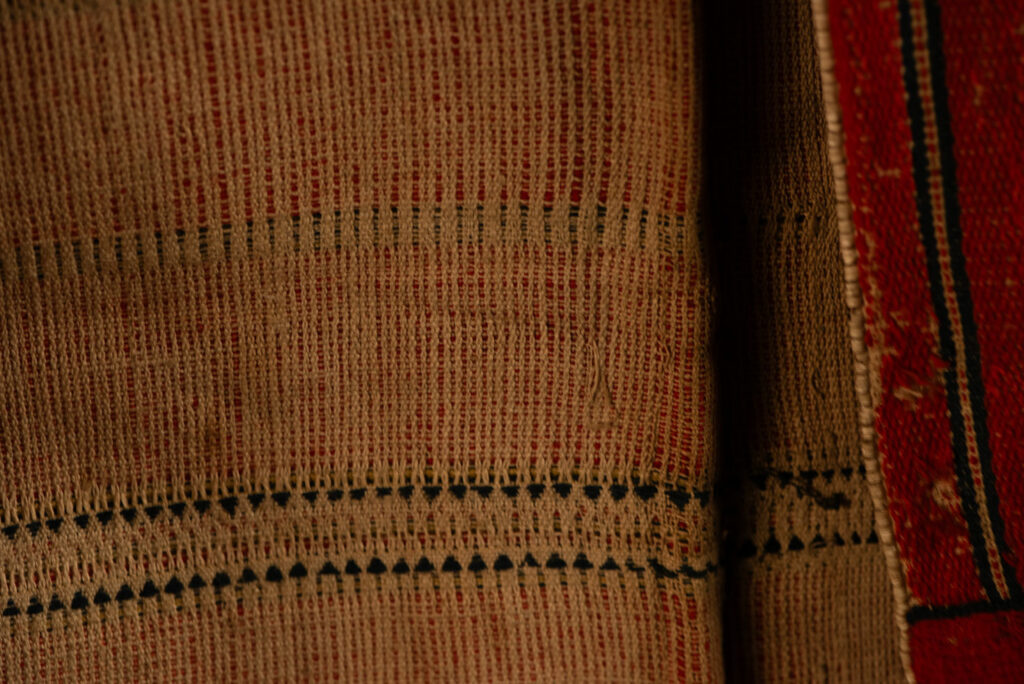 19 century Long men's jacket from the Atayal tribe, entirely woven in red with black and white stripes, and adorned with bone beads along the edges.