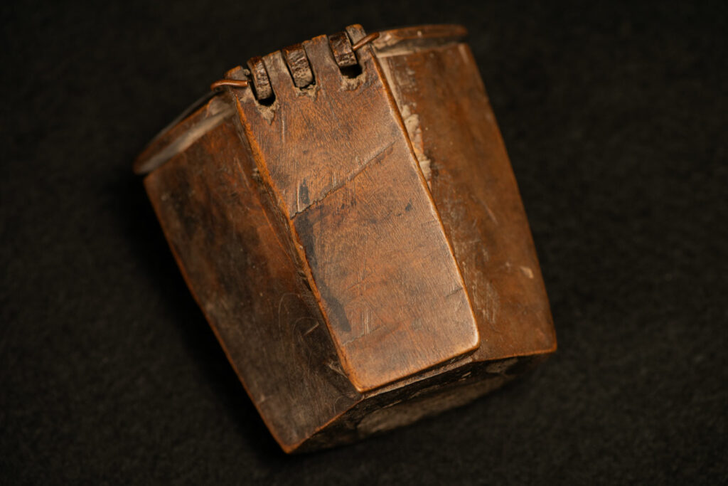 Wooden belt snuffbox from the Pingpu tribes, decorated with an engraving of a Chinese sage. It features a hinged lid carved from a single piece of wood and a section designed for attachment to the belt.