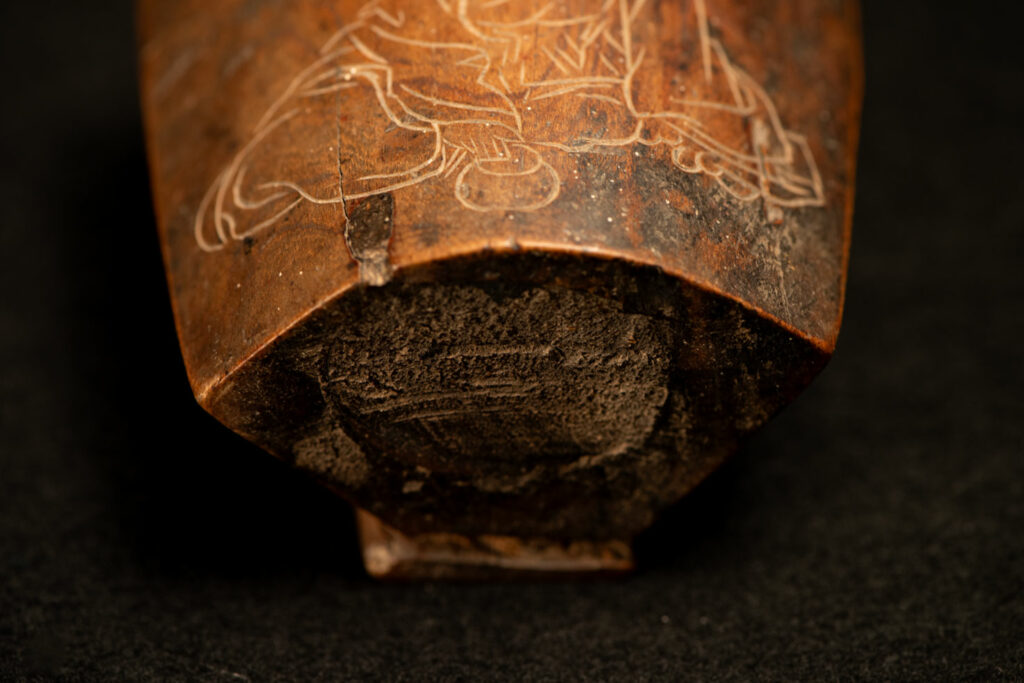 Wooden belt snuffbox from the Pingpu tribes, decorated with an engraving of a Chinese sage. It features a hinged lid carved from a single piece of wood and a section designed for attachment to the belt.