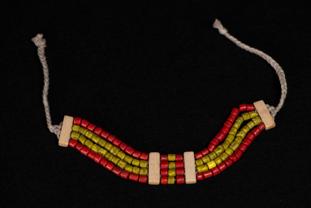 Bracelet from the Atayal tribe, made of yellow and red beads separated by polished bone bars, strung on a cord.