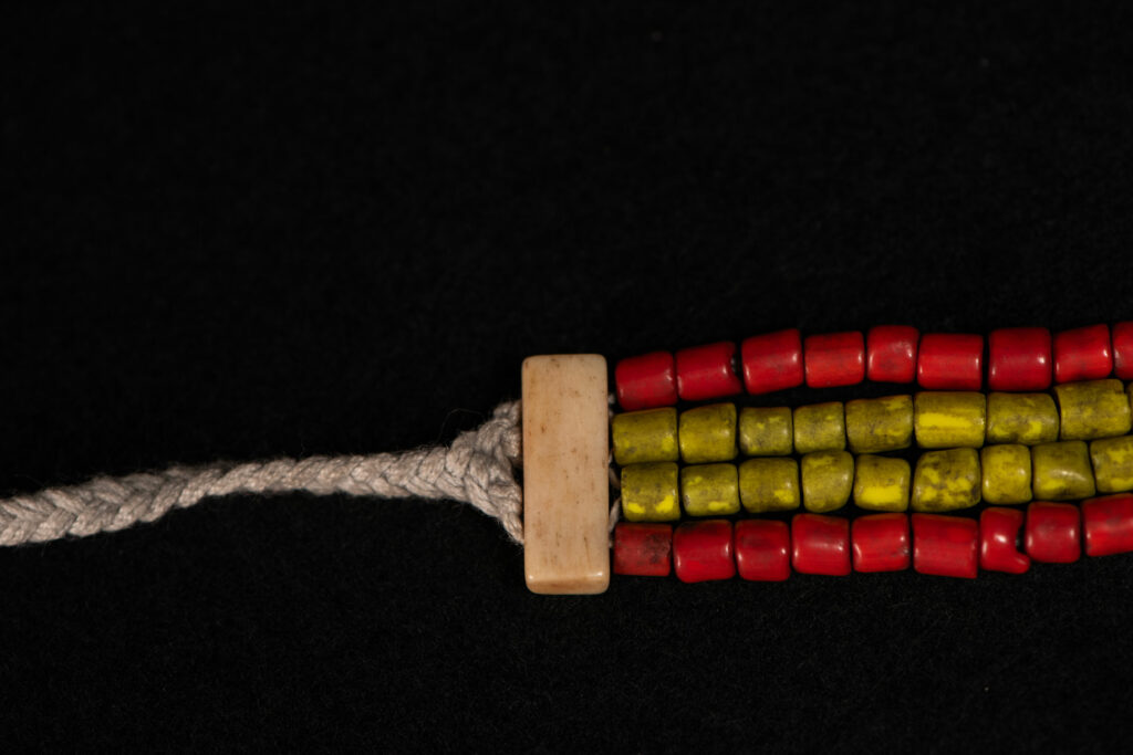 Bracelet from the Atayal tribe, made of yellow and red beads separated by polished bone bars, strung on a cord.