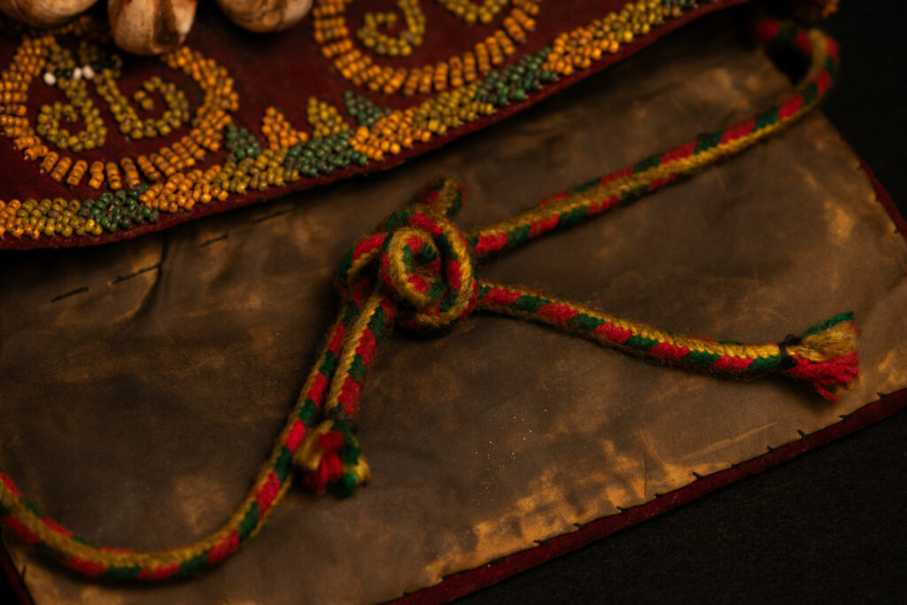 Paiwan tribe: ceremonial men's hat made of velvet, adorned with beadwork forming sacred snakes, and featuring a central rosette decorated with a round shell and boar tusks.