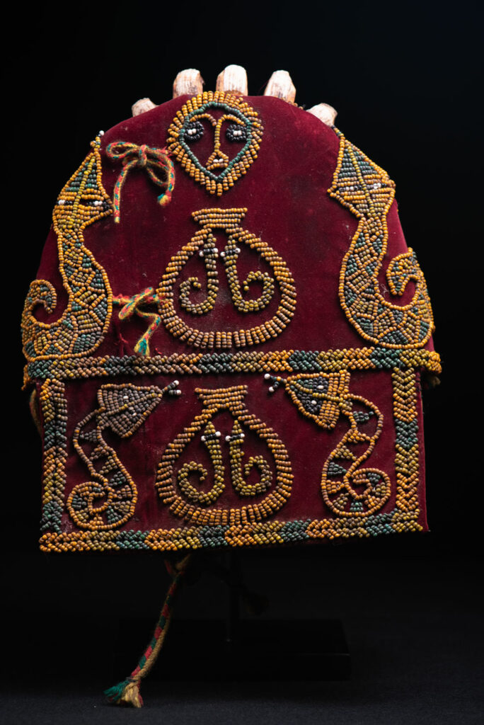 Paiwan tribe: ceremonial men's hat made of velvet, adorned with beadwork forming sacred snakes, and featuring a central rosette decorated with a round shell and boar tusks.