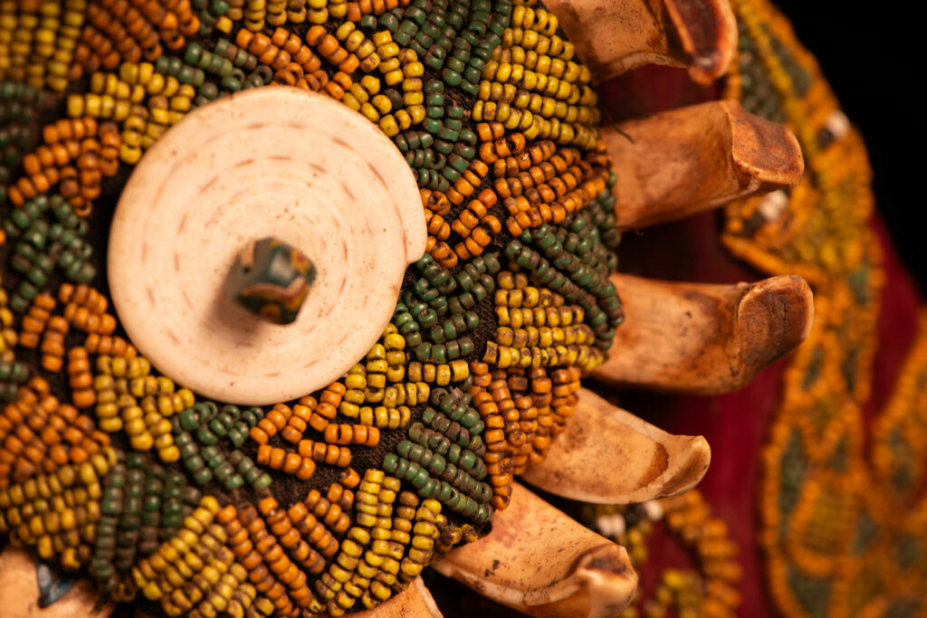 Paiwan tribe: ceremonial men's hat made of velvet, adorned with beadwork forming sacred snakes, and featuring a central rosette decorated with a round shell and boar tusks.
