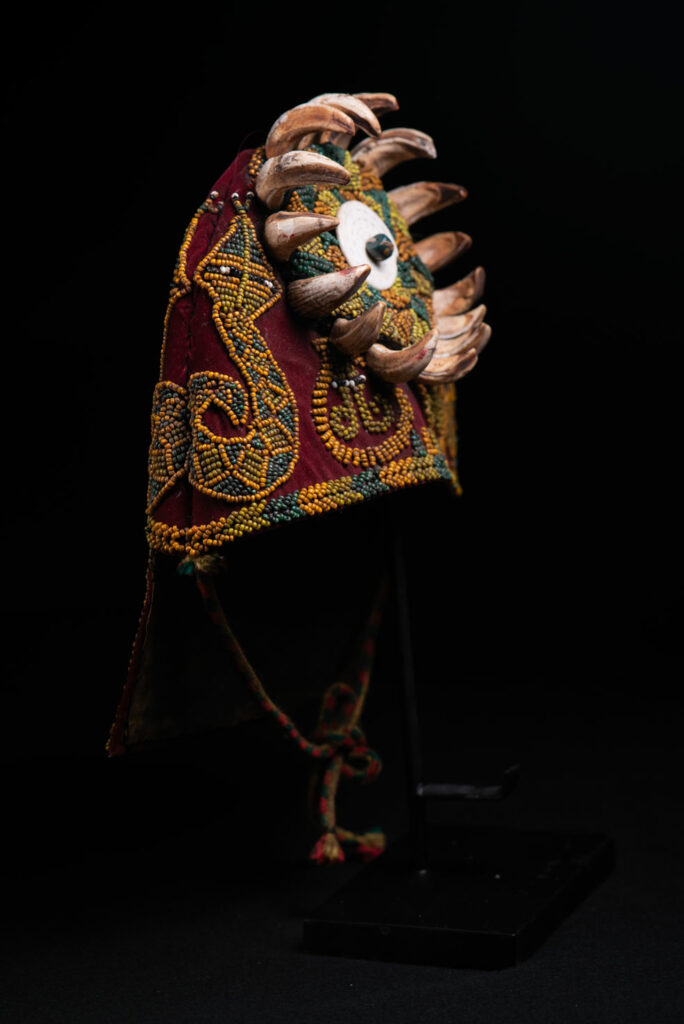 Paiwan tribe: ceremonial men's hat made of velvet, adorned with beadwork forming sacred snakes, and featuring a central rosette decorated with a round shell and boar tusks.
