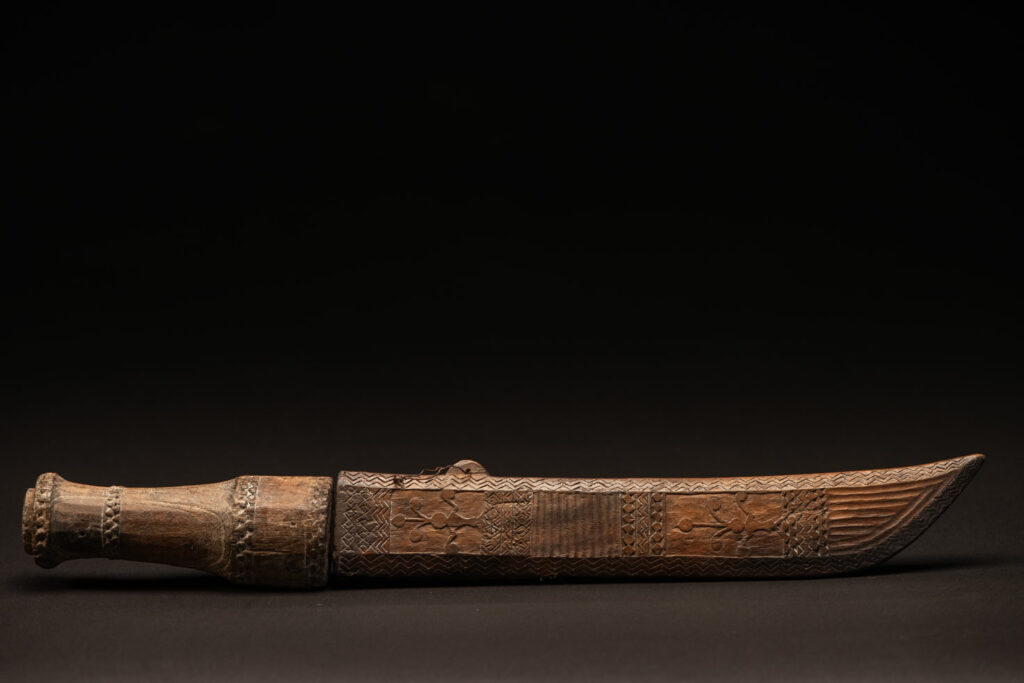 ‘Ipagan’ Knife and its sheath from the Yami (Tao) tribe. A fine example of the “Ipagan”, a short sword used to exorcise evil spirits but also to harvest. This sword, shorter than the Pararowai model, is notable for having both its handle and sheath carved with wave patterns, triangles, and the figure of the god Magamaog.