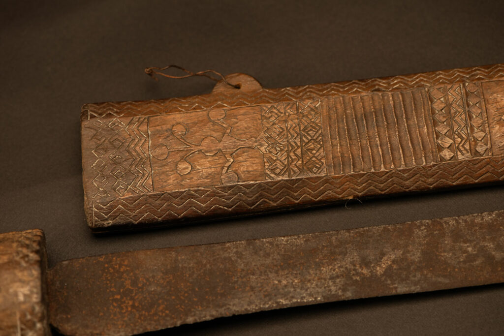 ‘Ipagan’ Knife and its sheath from the Yami (Tao) tribe. A fine example of the “Ipagan”, a short sword used to exorcise evil spirits but also to harvest. This sword, shorter than the Pararowai model, is notable for having both its handle and sheath carved with wave patterns, triangles, and the figure of the god Magamaog.