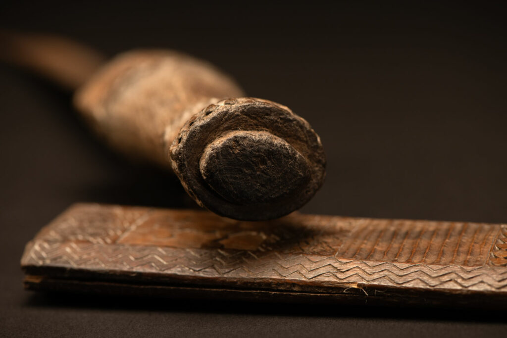 ‘Ipagan’ Knife and its sheath from the Yami (Tao) tribe. A fine example of the “Ipagan”, a short sword used to exorcise evil spirits but also to harvest. This sword, shorter than the Pararowai model, is notable for having both its handle and sheath carved with wave patterns, triangles, and the figure of the god Magamaog.