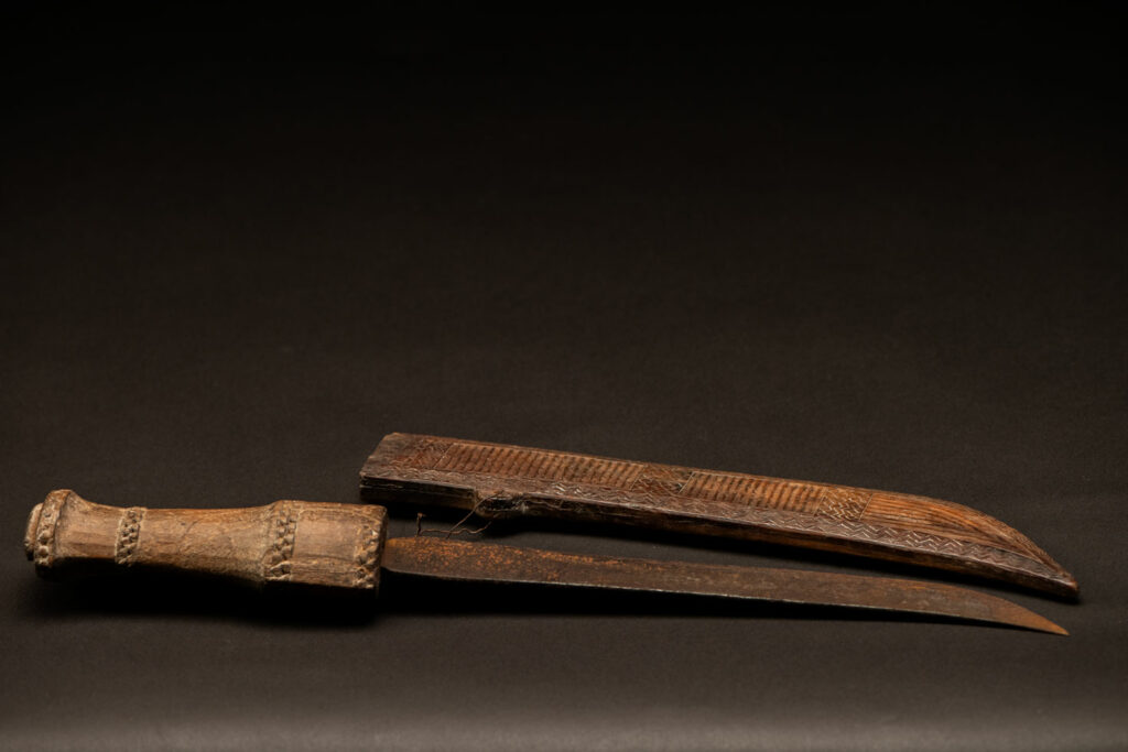 ‘Ipagan’ Knife and its sheath from the Yami (Tao) tribe. A fine example of the “Ipagan”, a short sword used to exorcise evil spirits but also to harvest. This sword, shorter than the Pararowai model, is notable for having both its handle and sheath carved with wave patterns, triangles, and the figure of the god Magamaog.