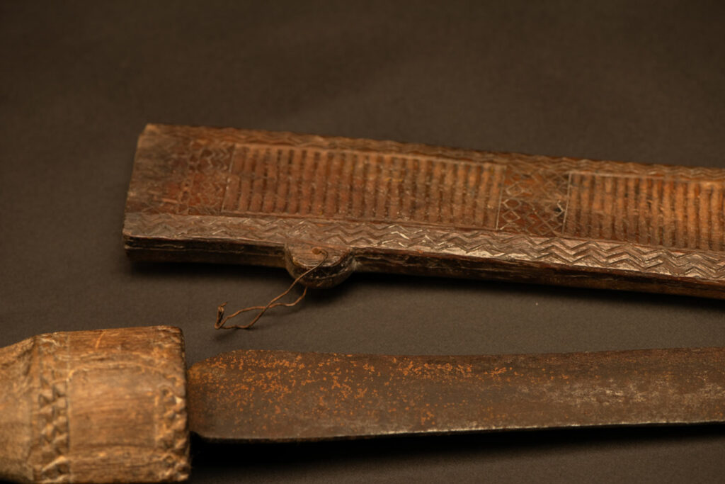 ‘Ipagan’ Knife and its sheath from the Yami (Tao) tribe. A fine example of the “Ipagan”, a short sword used to exorcise evil spirits but also to harvest. This sword, shorter than the Pararowai model, is notable for having both its handle and sheath carved with wave patterns, triangles, and the figure of the god Magamaog.