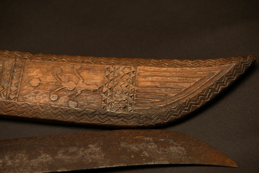 ‘Ipagan’ Knife and its sheath from the Yami (Tao) tribe. A fine example of the “Ipagan”, a short sword used to exorcise evil spirits but also to harvest. This sword, shorter than the Pararowai model, is notable for having both its handle and sheath carved with wave patterns, triangles, and the figure of the god Magamaog.