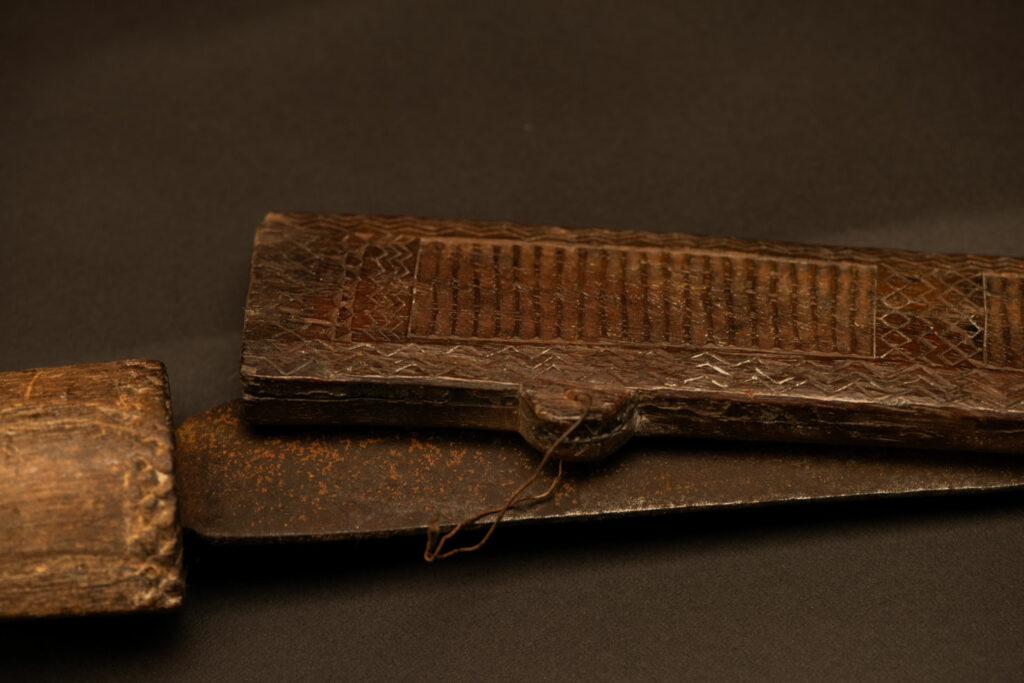 ‘Ipagan’ Knife and its sheath from the Yami (Tao) tribe. A fine example of the “Ipagan”, a short sword used to exorcise evil spirits but also to harvest. This sword, shorter than the Pararowai model, is notable for having both its handle and sheath carved with wave patterns, triangles, and the figure of the god Magamaog.
