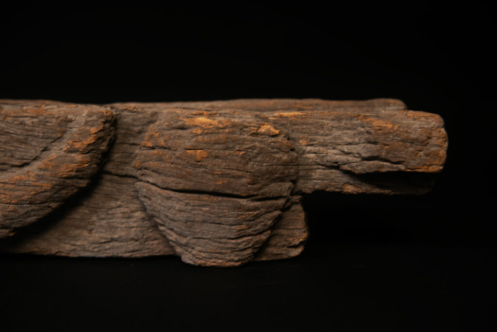 19th-century door lintel from the Paiwan tribe, carved with a pair of snakes facing each other and two human faces on either side. This Paiwan panel is heavily eroded and was probably placed above the entrance, exposed to the elements.