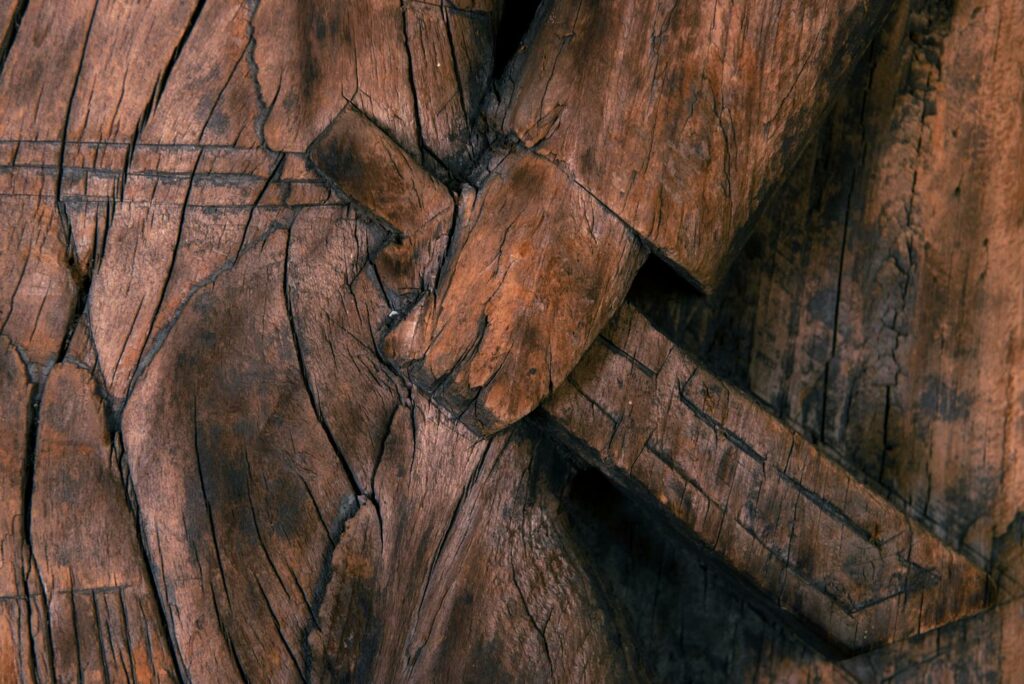 Paiwan tribe: massive 19th-century ancestral panel measuring over 2.5 meters, depicting a hunter wearing a Paiwan-style hat and holding a knife and a spear at his side. The carvings on his torso suggest he is dressed in a ceremonial vest and the shoulder belt traditionally worn by nobles. Due to its size, this panel was likely the central piece of the house.