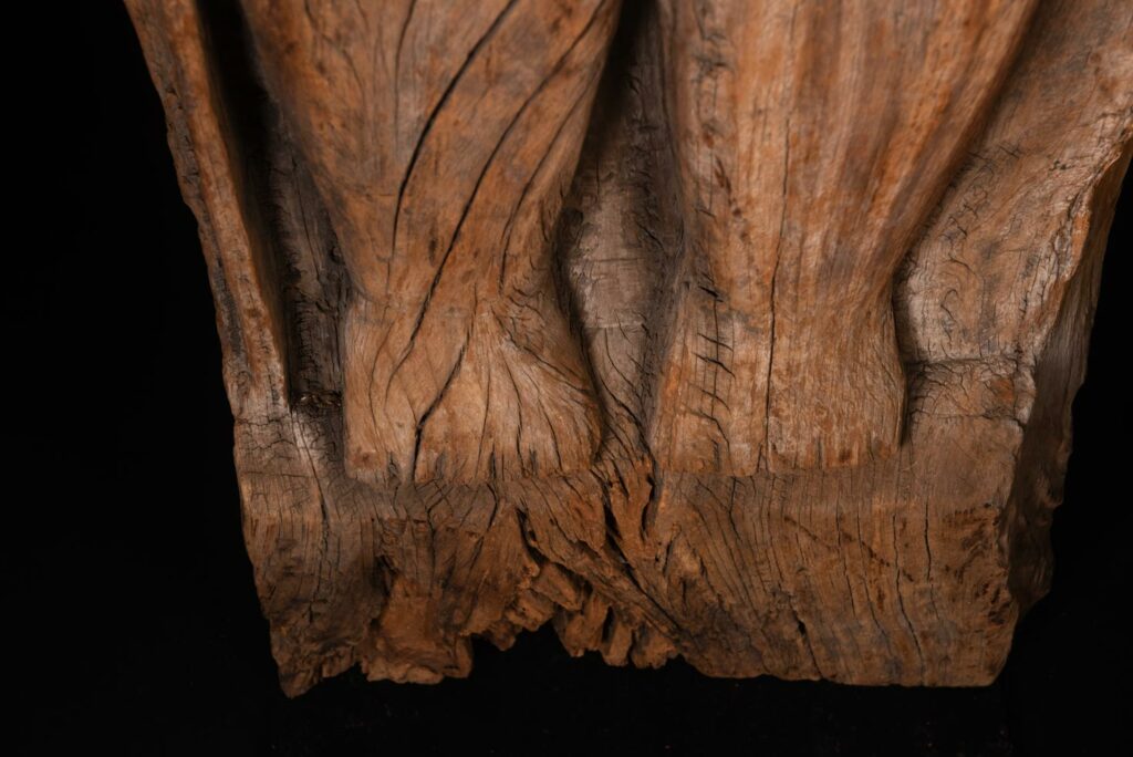 Paiwan tribe: massive 19th-century ancestral panel measuring over 2.5 meters, depicting a hunter wearing a Paiwan-style hat and holding a knife and a spear at his side. The carvings on his torso suggest he is dressed in a ceremonial vest and the shoulder belt traditionally worn by nobles. Due to its size, this panel was likely the central piece of the house.