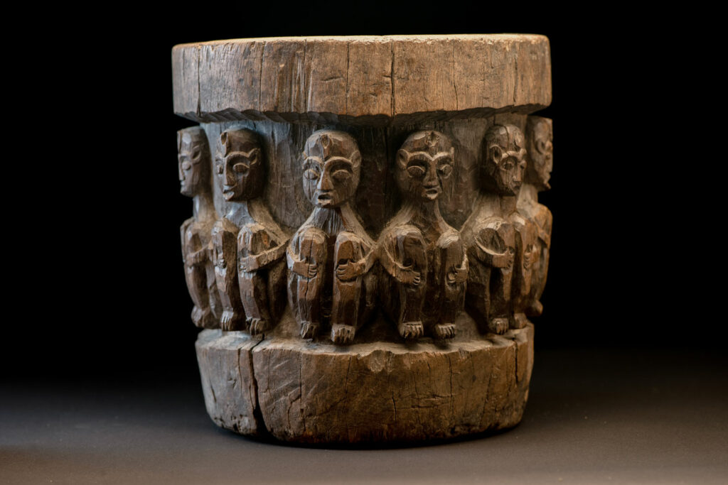 Small ancient mortar from the Paiwan tribe, richly carved around its circumference with a chain of crouching Paiwan figures.