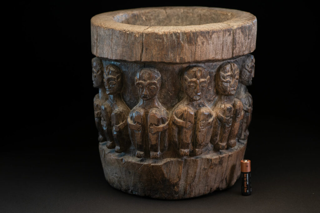 Small ancient mortar from the Paiwan tribe, richly carved around its circumference with a chain of crouching Paiwan figures.