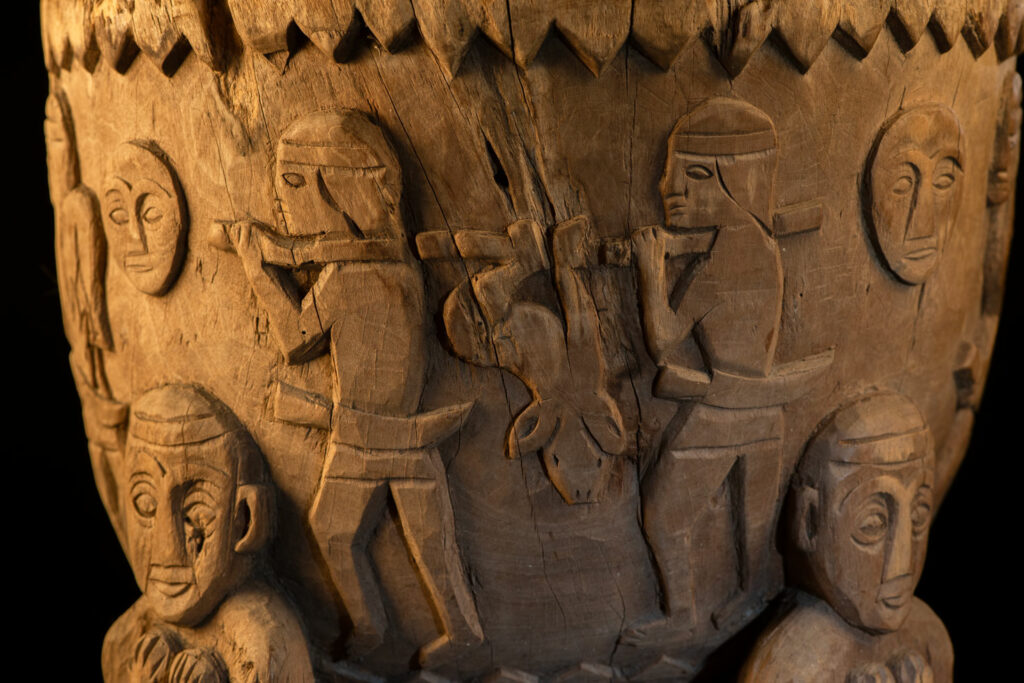 Ancient mortar from the Troukou (Pingpu) tribe, carved with crouching figures, human heads, and hunters carrying game or hunting with bows.