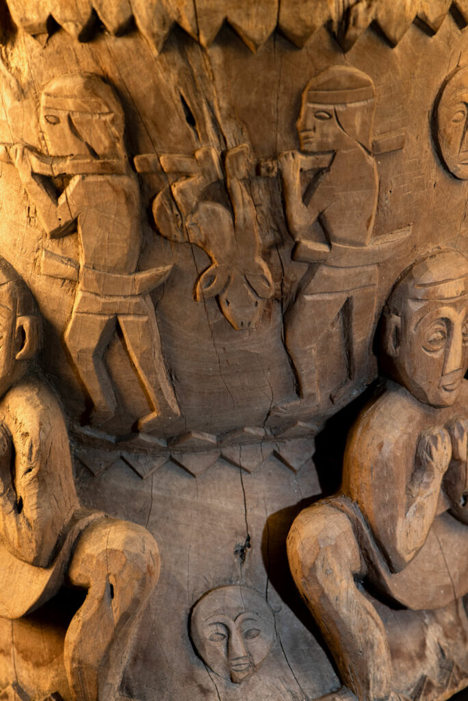 Ancient mortar from the Troukou (Pingpu) tribe, carved with crouching figures, human heads, and hunters carrying game or hunting with bows.