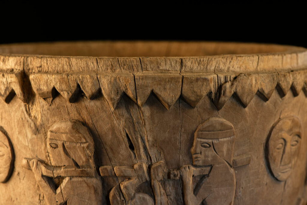 Ancient mortar from the Troukou (Pingpu) tribe, carved with crouching figures, human heads, and hunters carrying game or hunting with bows.