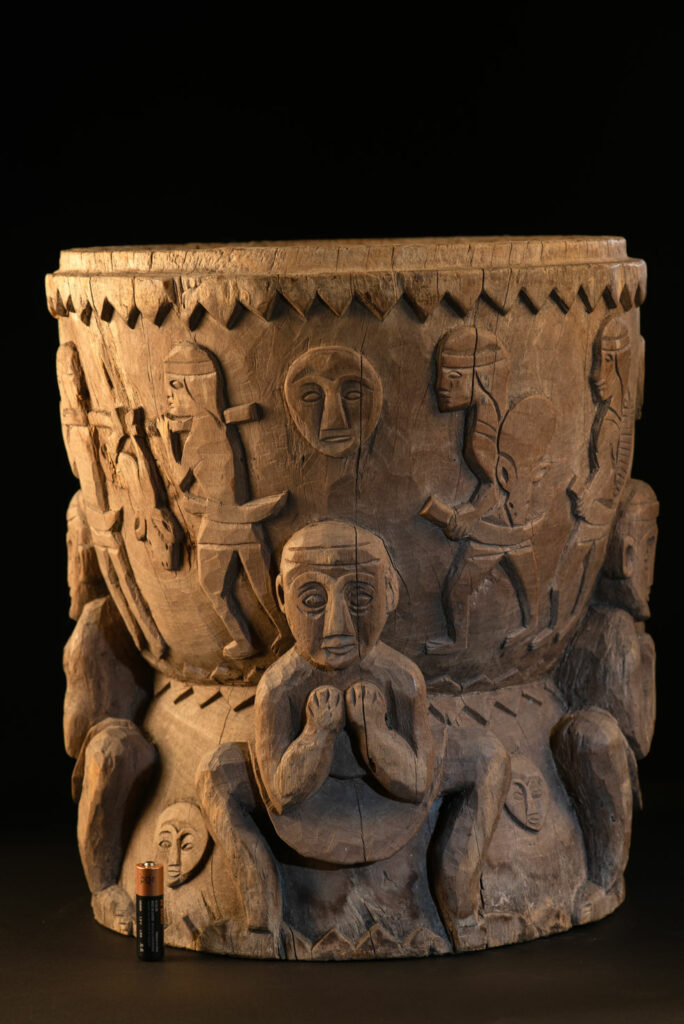 Ancient mortar from the Troukou (Pingpu) tribe, carved with crouching figures, human heads, and hunters carrying game or hunting with bows.