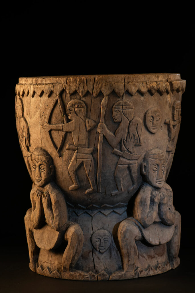 Ancient mortar from the Troukou (Pingpu) tribe, carved with crouching figures, human heads, and hunters carrying game or hunting with bows.