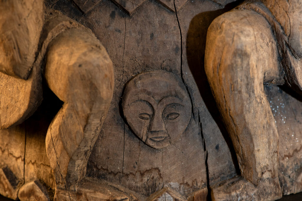 Ancient mortar from the Troukou (Pingpu) tribe, carved with crouching figures, human heads, and hunters carrying game or hunting with bows.