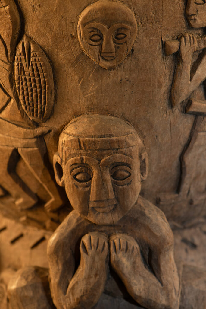 Ancient mortar from the Troukou (Pingpu) tribe, carved with crouching figures, human heads, and hunters carrying game or hunting with bows.