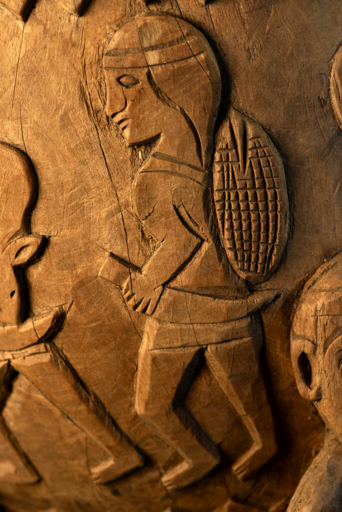 Ancient mortar from the Troukou (Pingpu) tribe, carved with crouching figures, human heads, and hunters carrying game or hunting with bows.