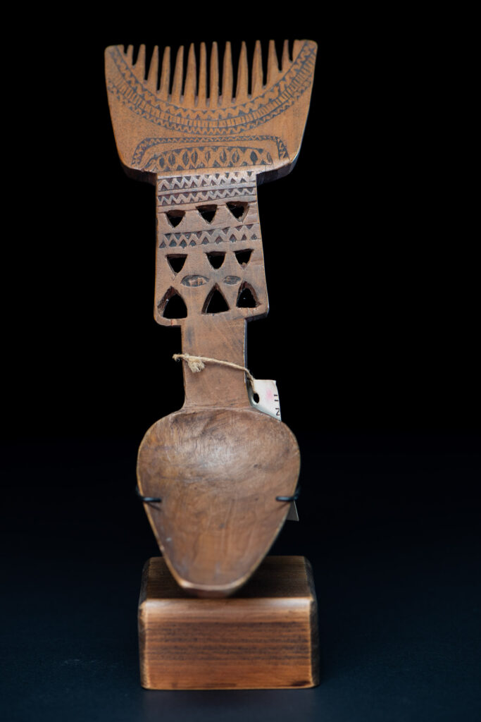 Paiwan tribe ancient spoon and comb together done inside a yellow wood and carved with geometric pattern .