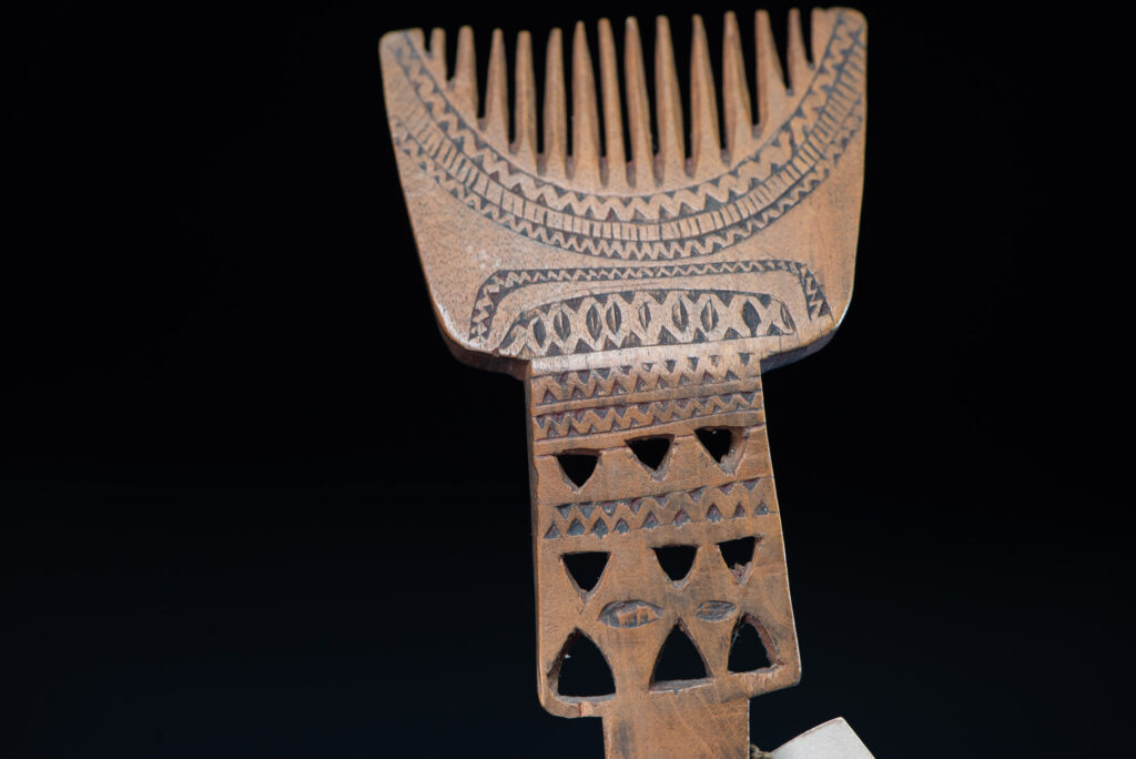 Paiwan tribe ancient spoon and comb together done inside a yellow wood and carved with geometric pattern .