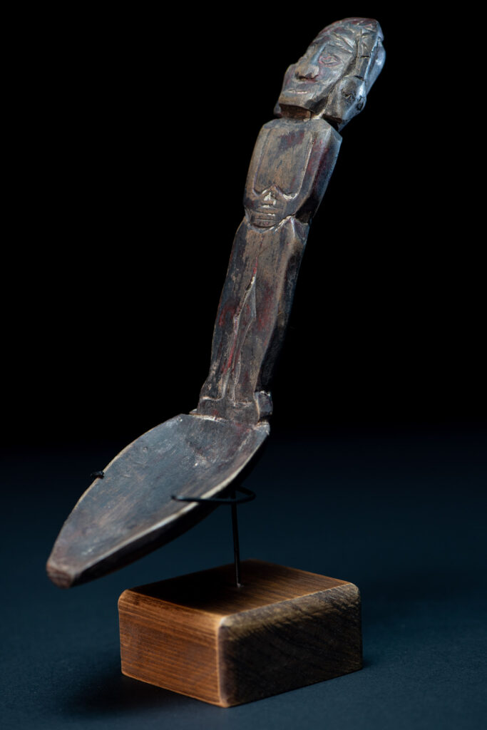 Paiwan tribe ancient wood spoon carved with a standing picture of warrior with a two-headed snake encircling the head of the upper figure. Some red tint remains.