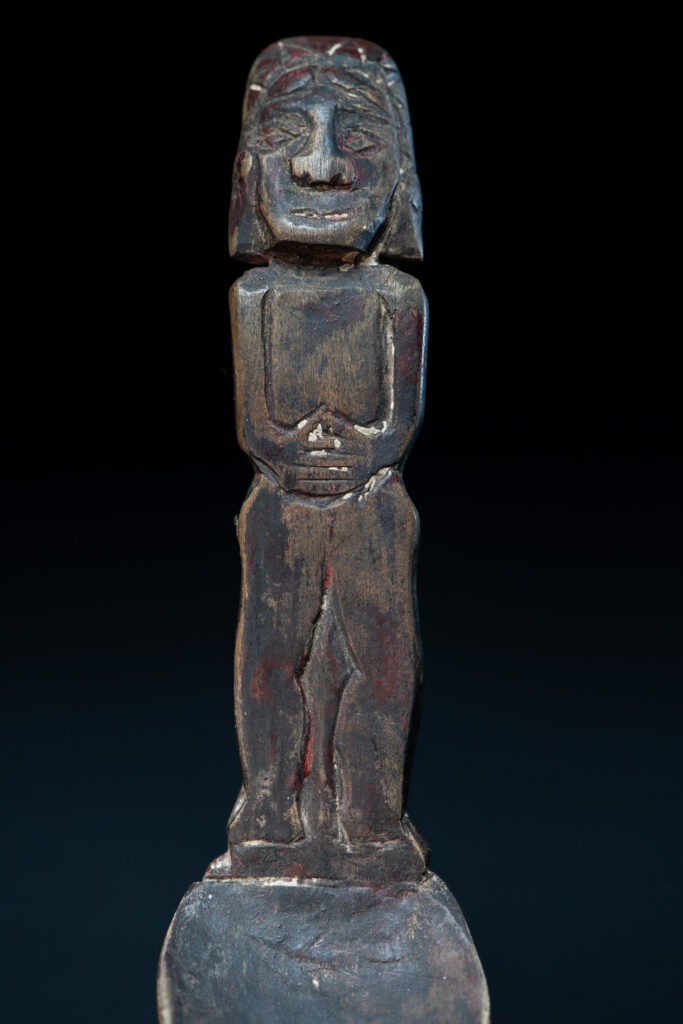 Paiwan tribe ancient wood spoon carved with a standing picture of warrior with a two-headed snake encircling the head of the upper figure. Some red tint remains.