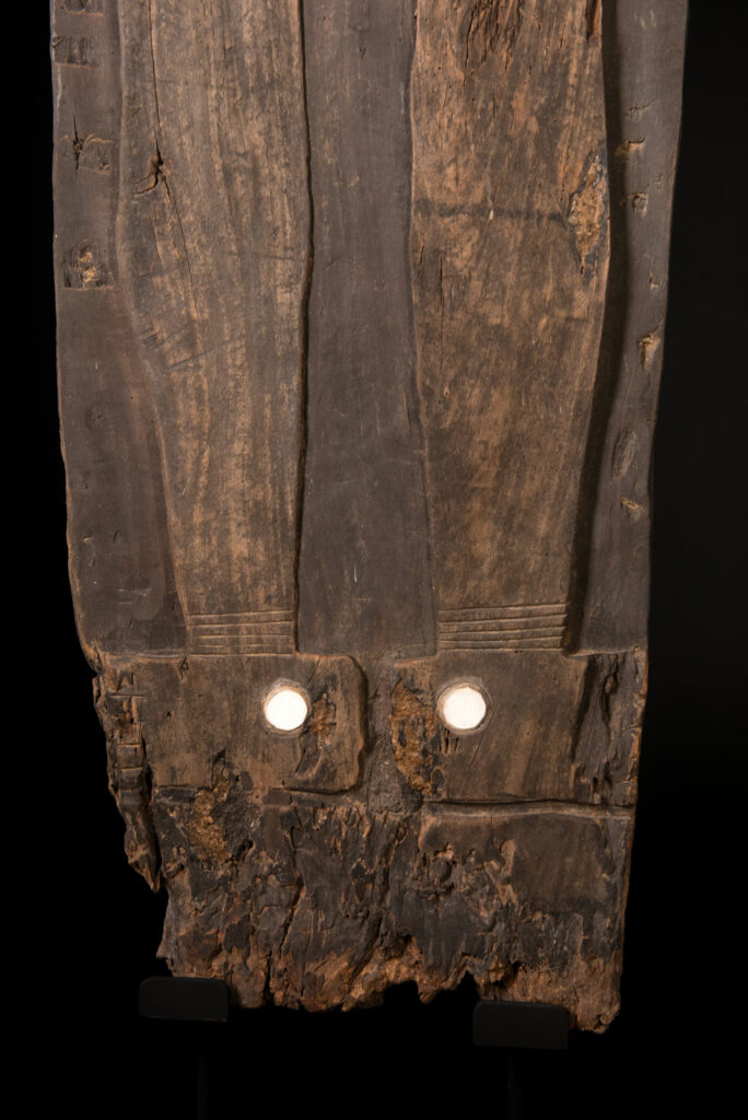 Pair of ancestor panels from the Paiwan tribe, depicting a male and a female figure, both wearing feathered headdresses — symbols of valor and vigor. The panels are inlaid with porcelain circles at the eyes, mouth, and waist, representing the ceremonial belts they wear.