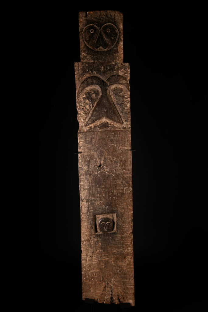 Rare and massive early 19th-century panel from the East Coast Paiwan tribe, carved in the Taimali style. It features a prominent central nose, a stylized face at the top, and another face carved at the bottom — a characteristic design of the Southeastern Paiwan tradition.