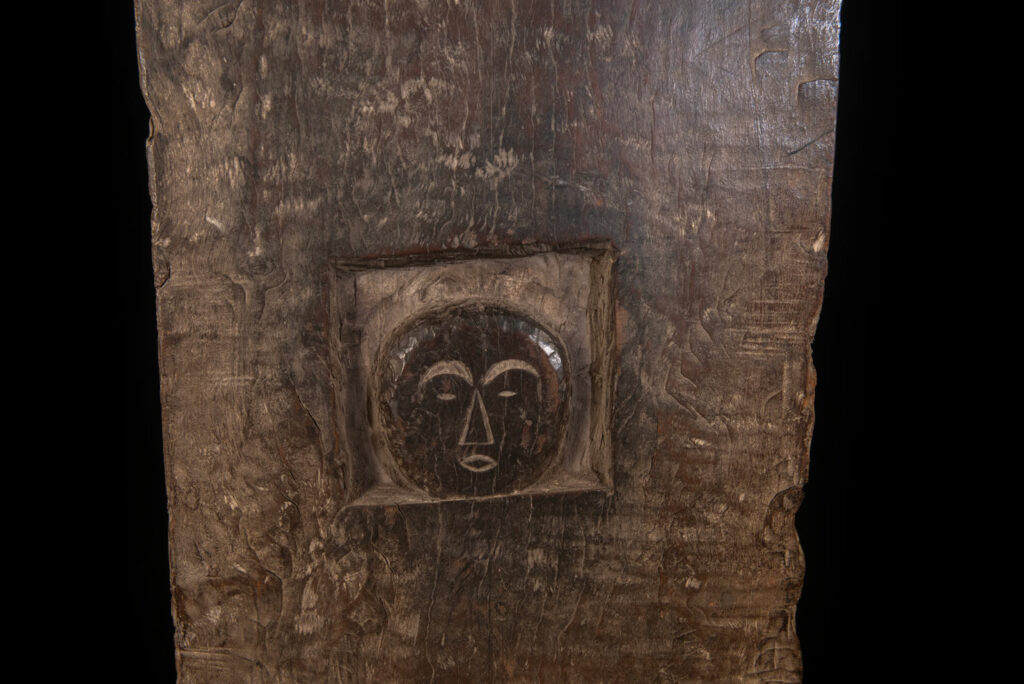 Rare and massive early 19th-century panel from the East Coast Paiwan tribe, carved in the Taimali style. It features a prominent central nose, a stylized face at the top, and another face carved at the bottom — a characteristic design of the Southeastern Paiwan tradition.