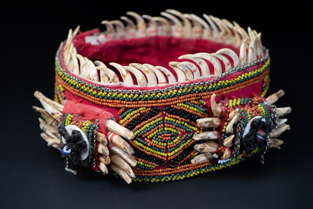 Women's headdress from the Paiwan tribe, made of green, yellow, red, and black beads arranged in geometric patterns, and topped with boar tusks.