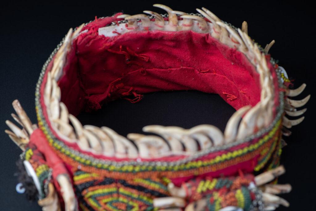 Women's headdress from the Paiwan tribe, made of green, yellow, red, and black beads arranged in geometric patterns, and topped with boar tusks.