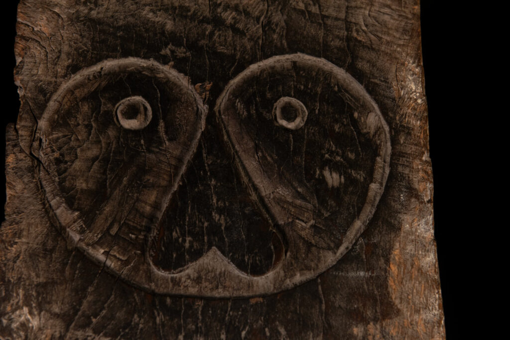 Rare and massive early 19th-century panel from the East Coast Paiwan tribe, carved in the Taimali style. It features a prominent central nose, a stylized face at the top, and another face carved at the bottom — a characteristic design of the Southeastern Paiwan tradition.